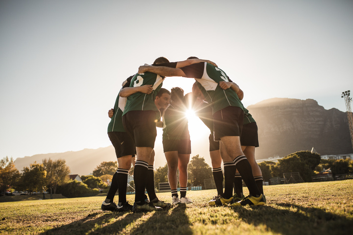 Group of people huddled in soccer uniforms for a field day fundraiser