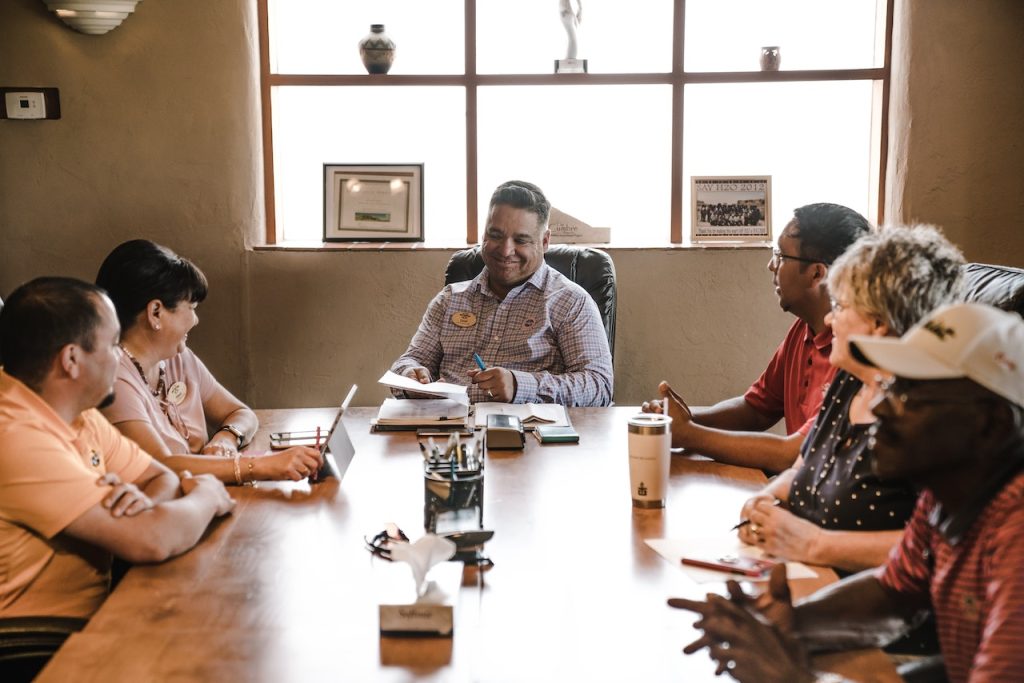 board meeting with diverse individuals sitting around the board table